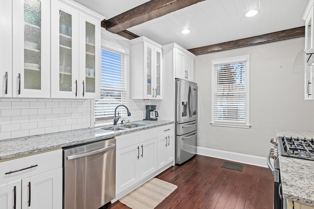 kitchen featuring tasteful backsplash, appliances with stainless steel finishes, a sink, beamed ceiling, and baseboards