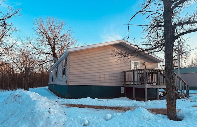 snow covered property with stairway and a deck