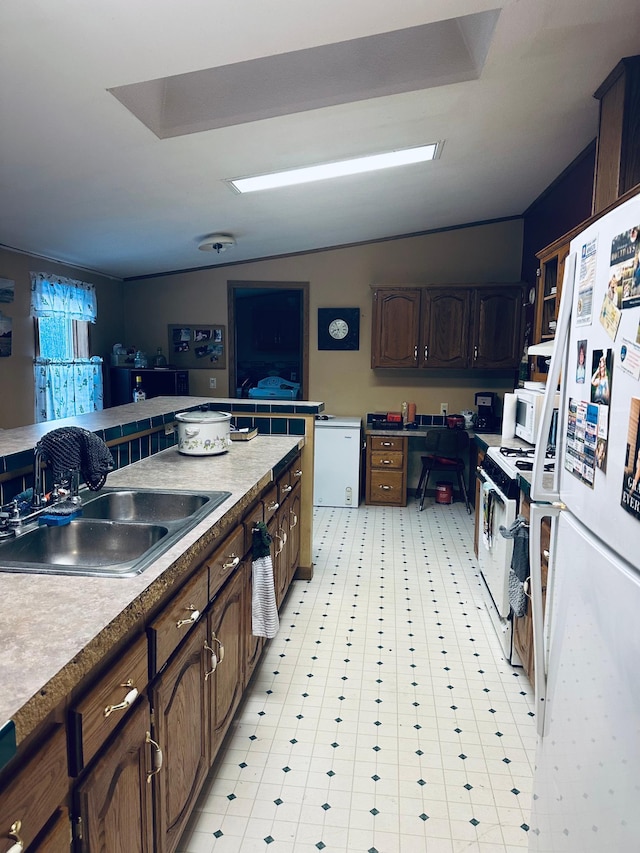 kitchen featuring vaulted ceiling, light floors, white appliances, and a sink