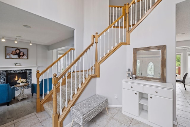 3679 Commonwealth Rd, Woodbury, MN 55125 - stairs with tile patterned floors, a tile fireplace, baseboards, track lighting, and a towering ceiling