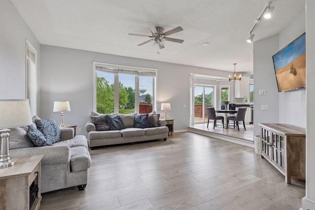 3679 Commonwealth Rd, Woodbury, MN 55125 - living area with a chandelier, ceiling fan, a textured ceiling, wood finished floors, and rail lighting