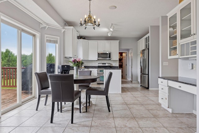 3679 Commonwealth Rd, Woodbury, MN 55125 - dining area with a chandelier, light tile patterned flooring, a textured ceiling, a desk, and baseboards