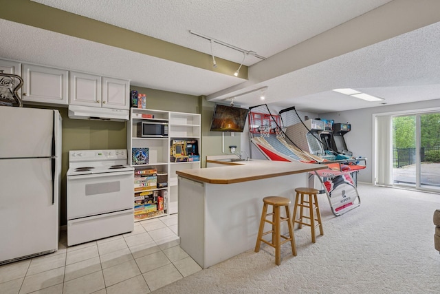 3679 Commonwealth Rd, Woodbury, MN 55125 - kitchen with white appliances, under cabinet range hood, track lighting, a textured ceiling, and a breakfast bar area