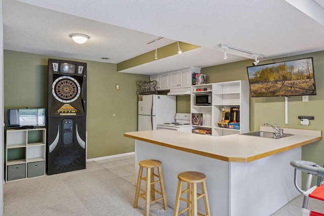3679 Commonwealth Rd, Woodbury, MN 55125 - kitchen featuring white appliances, a sink, a textured ceiling, a breakfast bar, and a peninsula