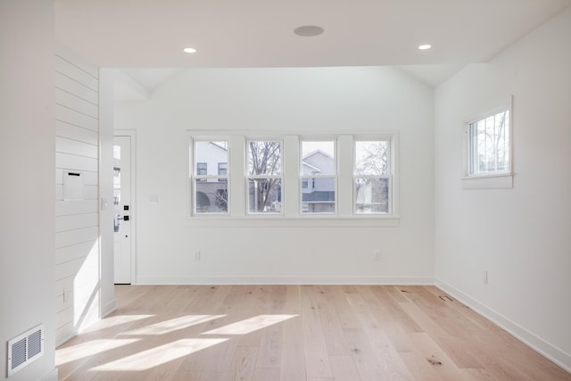 empty room with visible vents, baseboards, recessed lighting, vaulted ceiling, and light wood-style floors