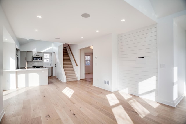 unfurnished living room with recessed lighting, visible vents, light wood-style flooring, and stairway