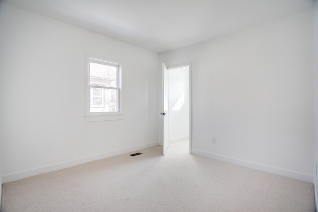 empty room featuring light carpet, visible vents, and baseboards