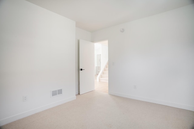 empty room featuring visible vents, light carpet, and baseboards