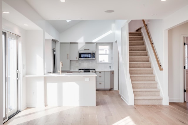 kitchen with gray cabinets, stainless steel appliances, light wood-style floors, and a sink