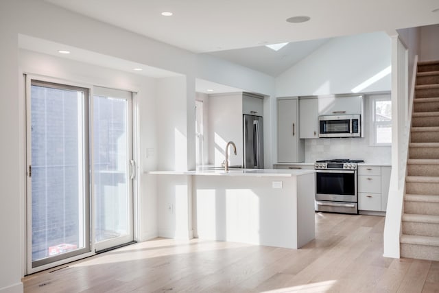 kitchen with lofted ceiling, light wood-style flooring, light countertops, appliances with stainless steel finishes, and modern cabinets