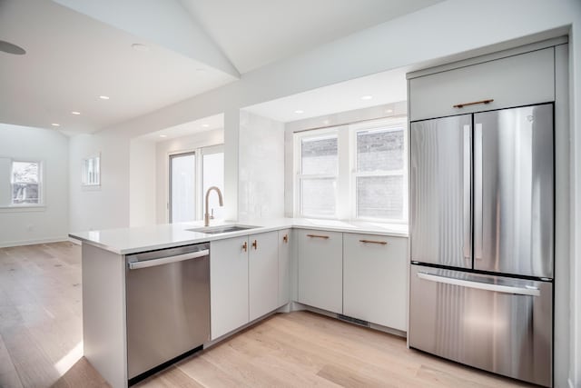 kitchen featuring light wood-style flooring, appliances with stainless steel finishes, light countertops, and a sink