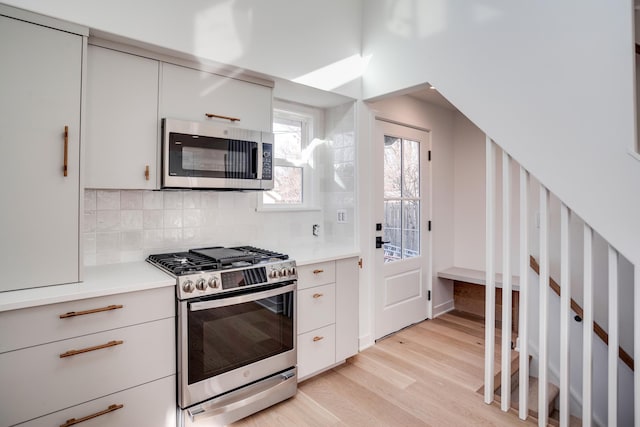 kitchen featuring tasteful backsplash, light wood-style flooring, appliances with stainless steel finishes, and light countertops