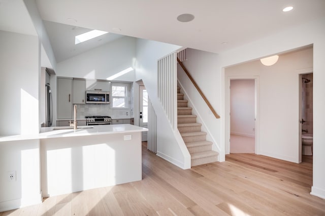 kitchen featuring a peninsula, stainless steel appliances, a sink, light countertops, and light wood-type flooring