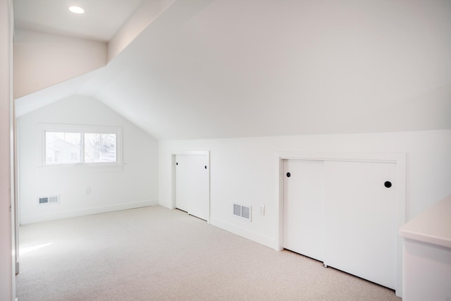 additional living space with visible vents, lofted ceiling, carpet, and baseboards