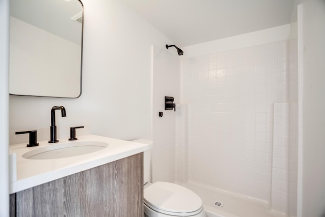 bathroom featuring vanity, toilet, and tiled shower