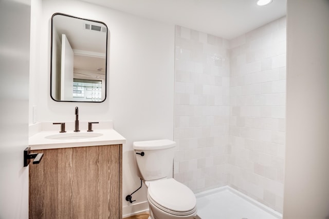 full bathroom with tiled shower, toilet, and vanity