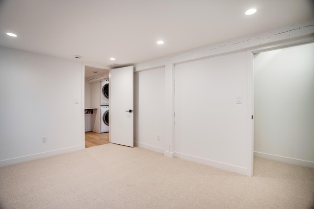 finished basement with recessed lighting, baseboards, light colored carpet, and stacked washing maching and dryer