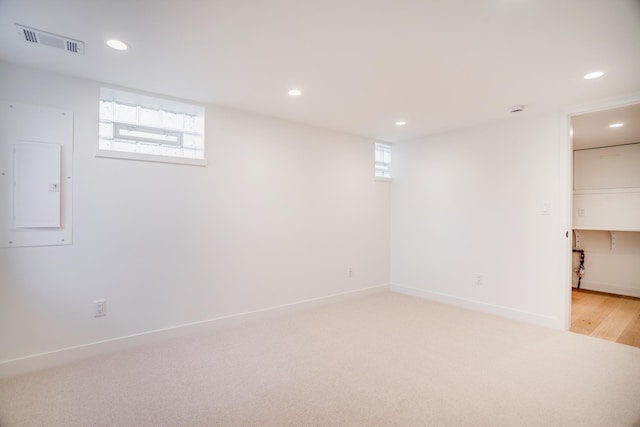 below grade area with electric panel, visible vents, recessed lighting, and light carpet