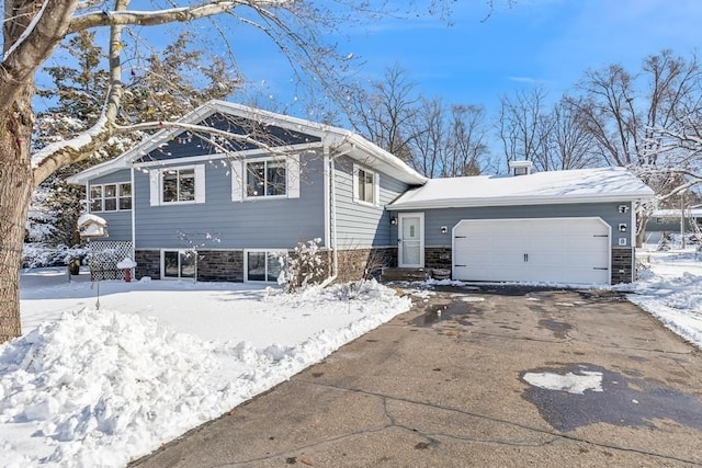 view of front of property with stone siding, driveway, and an attached garage