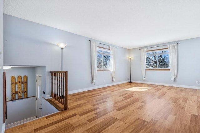 spare room featuring baseboards and light wood finished floors