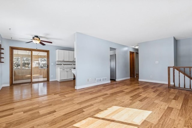 unfurnished living room with light wood-style floors, visible vents, ceiling fan, and baseboards