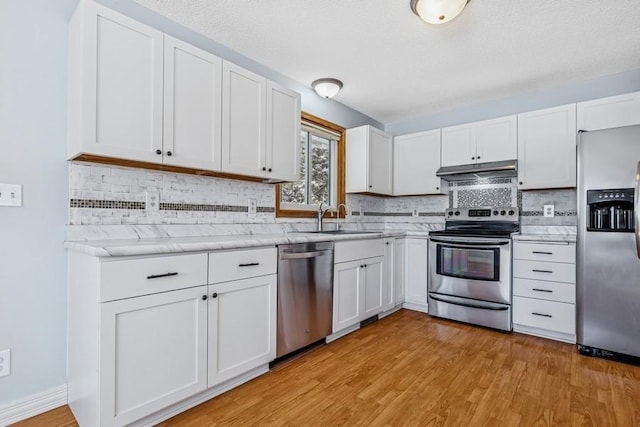 kitchen featuring appliances with stainless steel finishes, light wood-type flooring, white cabinets, and under cabinet range hood