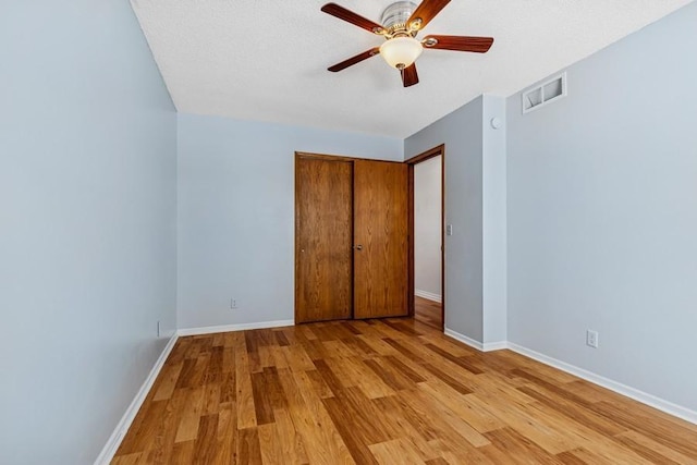 unfurnished bedroom with ceiling fan, visible vents, baseboards, a closet, and light wood finished floors