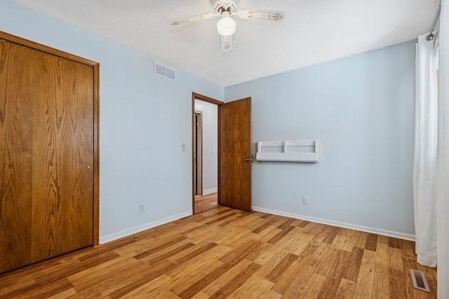 unfurnished bedroom with a closet, wood finished floors, visible vents, and baseboards