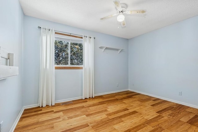 unfurnished room featuring baseboards, light wood-type flooring, visible vents, and a ceiling fan