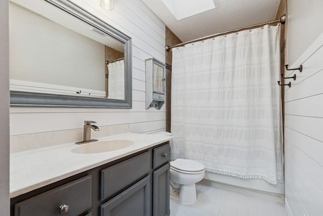 full bath featuring toilet, a skylight, wooden walls, and vanity