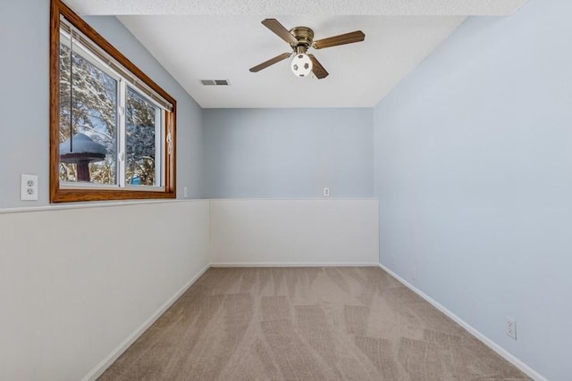 carpeted spare room with ceiling fan, visible vents, and baseboards