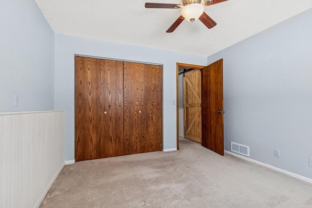 unfurnished bedroom featuring visible vents, ceiling fan, carpet, a textured ceiling, and a closet