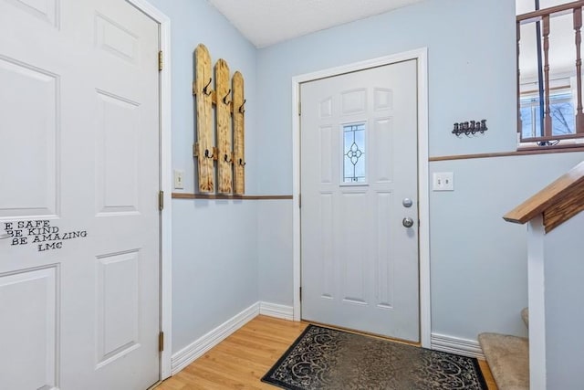 entryway featuring light wood-style flooring, stairs, and baseboards