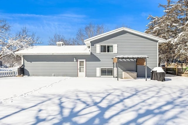 snow covered back of property with fence