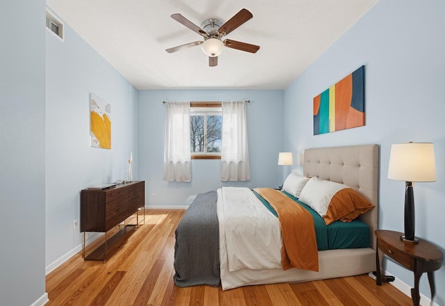 bedroom featuring visible vents, ceiling fan, baseboards, and wood finished floors