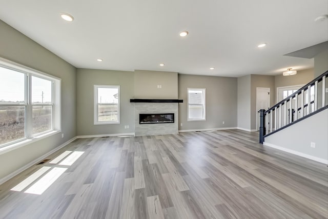 unfurnished living room with wood finished floors, stairway, recessed lighting, and baseboards