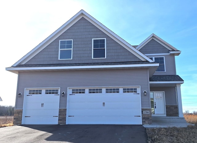 craftsman inspired home featuring stone siding, driveway, a garage, and roof with shingles