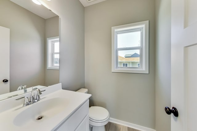 bathroom with baseboards, toilet, wood finished floors, and vanity