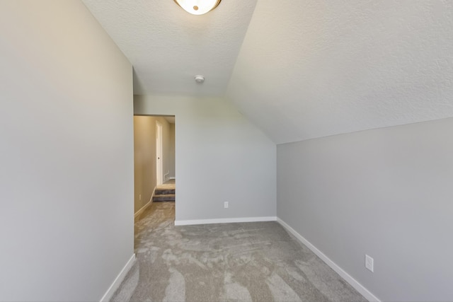 bonus room featuring lofted ceiling, carpet flooring, baseboards, and a textured ceiling