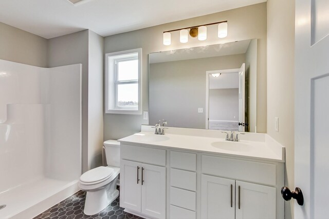 bathroom with double vanity, toilet, walk in shower, and a sink