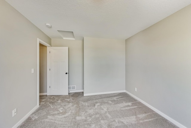 spare room featuring visible vents, carpet, baseboards, and a textured ceiling