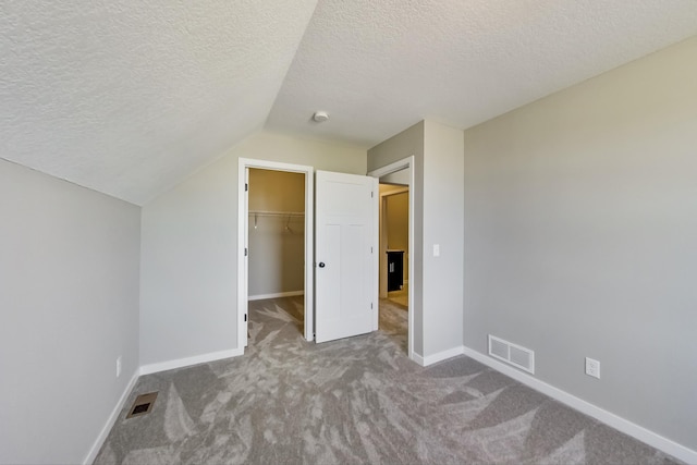 unfurnished bedroom featuring visible vents, carpet floors, baseboards, and vaulted ceiling