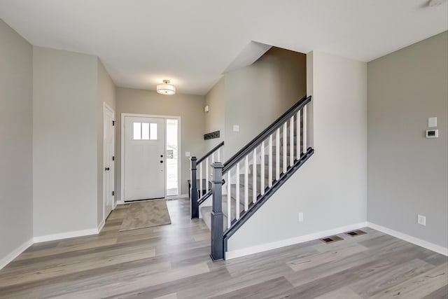 entryway featuring baseboards, light wood-style flooring, and stairs