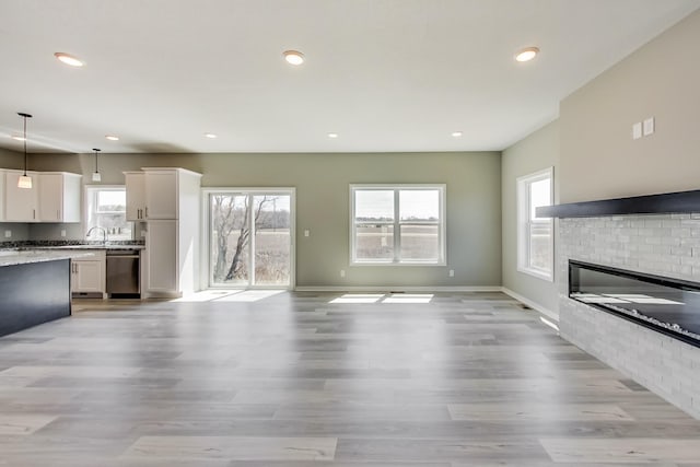 unfurnished living room with a healthy amount of sunlight, baseboards, and light wood finished floors
