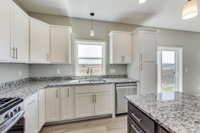kitchen featuring white cabinets, light stone counters, a sink, light wood finished floors, and stainless steel appliances