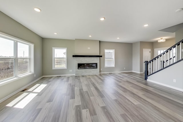 unfurnished living room featuring baseboards, wood finished floors, and stairway