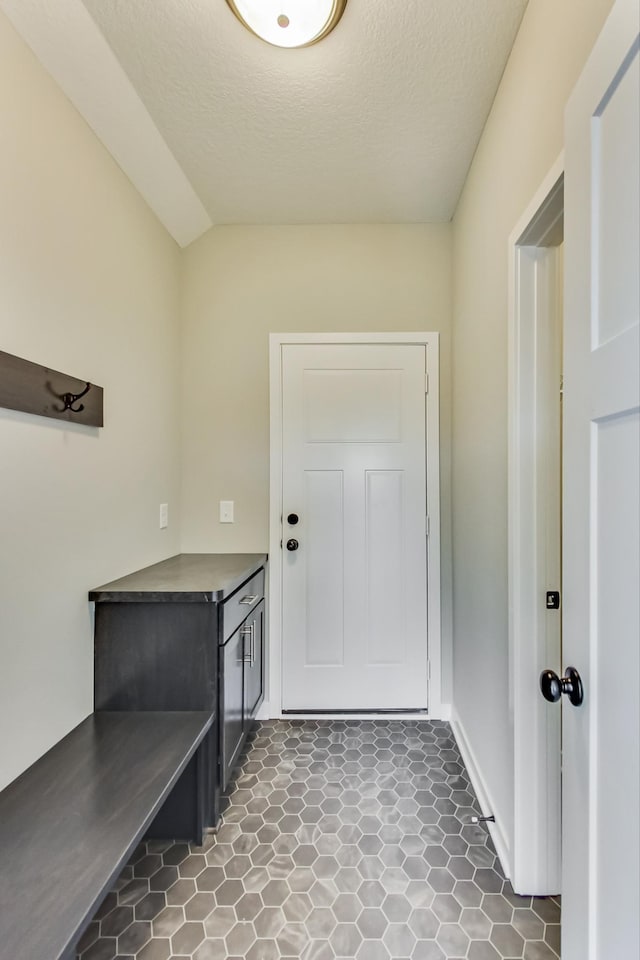 doorway to outside with a textured ceiling and lofted ceiling