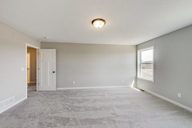 empty room featuring visible vents, carpet flooring, and baseboards