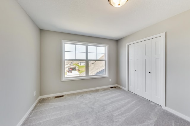unfurnished bedroom featuring baseboards, visible vents, carpet, and a closet