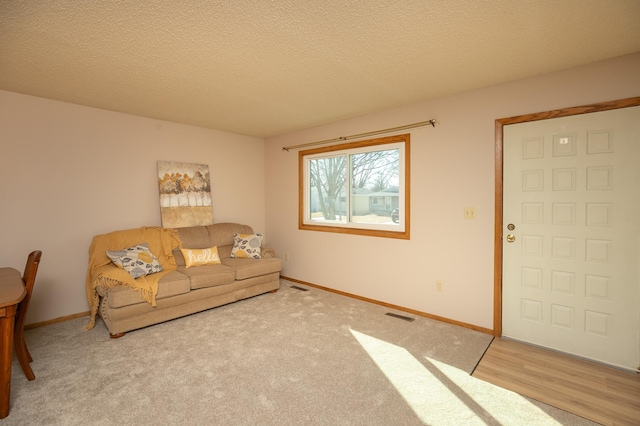 living room featuring baseboards, visible vents, and a textured ceiling